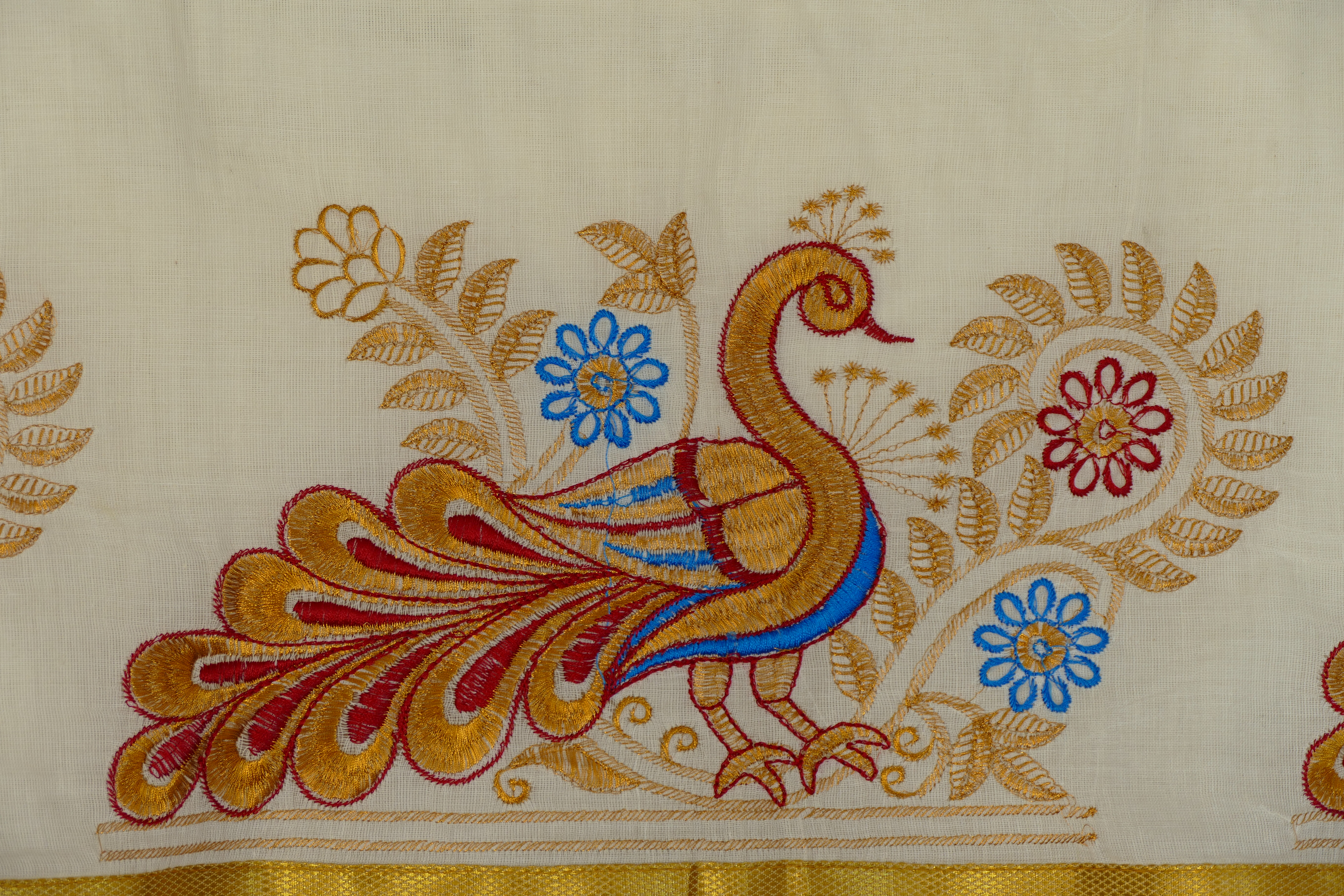 Detailed gold and coloured embroidery on ivory textile